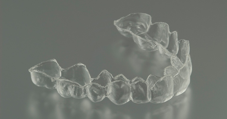 An Invisalign Retainer on Grey Background